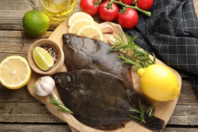 Photo of Fresh flounder fish, spices and products on wooden table, flat lay. Raw seafood