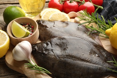 Photo of Fresh flounder fish, spices and products on wooden table, closeup. Raw seafood