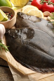 Photo of Fresh flounder fish, spices and products on wooden table, closeup. Raw seafood