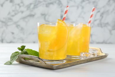 Photo of Refreshing soda water with orange slices in glasses and mint on white wooden table, closeup