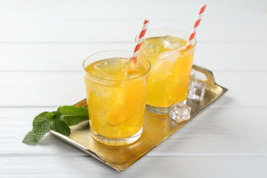 Photo of Refreshing soda water with orange slices in glasses and mint on white wooden table, closeup