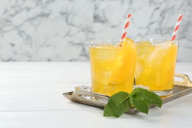 Photo of Refreshing soda water with orange slices in glasses and mint on white wooden table, closeup. Space for text