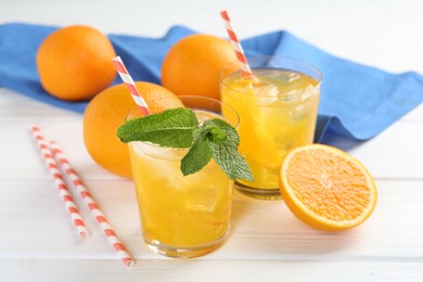 Photo of Refreshing soda water with orange slices in glasses, mint and fresh fruits on white wooden table, closeup