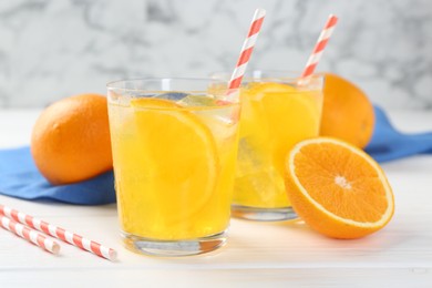 Photo of Refreshing soda water with orange slices in glasses and fresh fruits on white wooden table, closeup