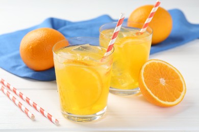 Photo of Refreshing soda water with orange slices in glasses and fresh fruits on white wooden table, closeup