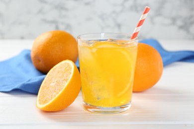 Photo of Refreshing soda water with orange slice in glass and fresh fruits on white wooden table, closeup
