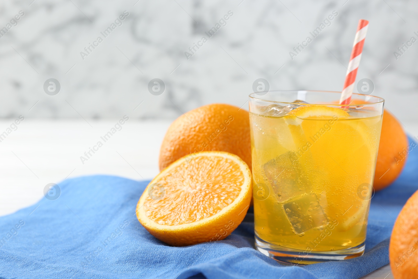 Photo of Refreshing soda water with orange slice in glass and fresh fruits on table, closeup. Space for text