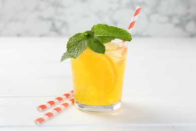 Photo of Refreshing soda water with orange slice in glass and mint on white wooden table, closeup