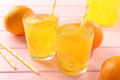 Photo of Refreshing soda water with orange slices in glasses and fresh fruits on pink wooden table, closeup
