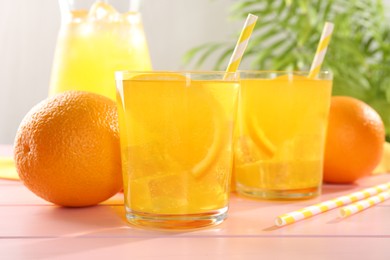 Photo of Refreshing soda water with orange slices in glasses, jug and fresh fruits on pink wooden table, closeup