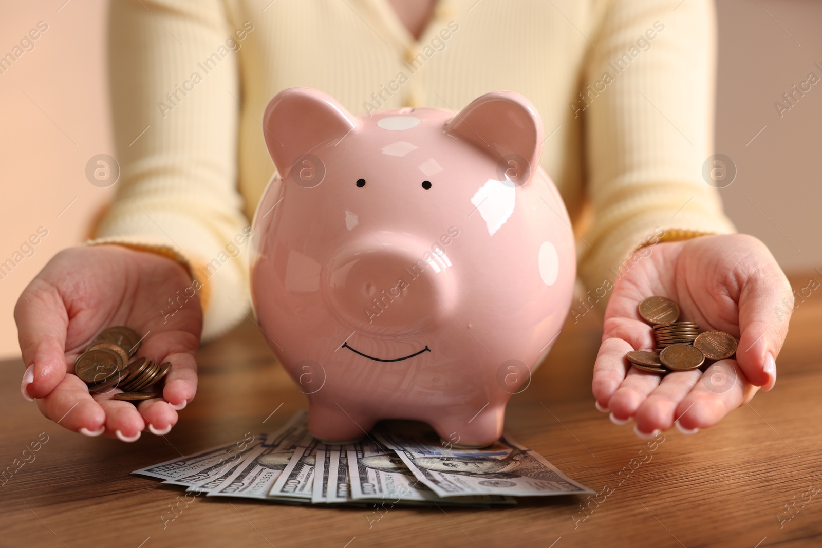 Woman with piggybank and money at wooden table, closeup Photo of Woman with piggybank and money at wooden table, closeup