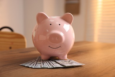 Photo of Piggybank and dollar banknotes on wooden table