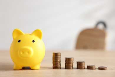 Photo of Piggybank and coins on wooden table. Space for text