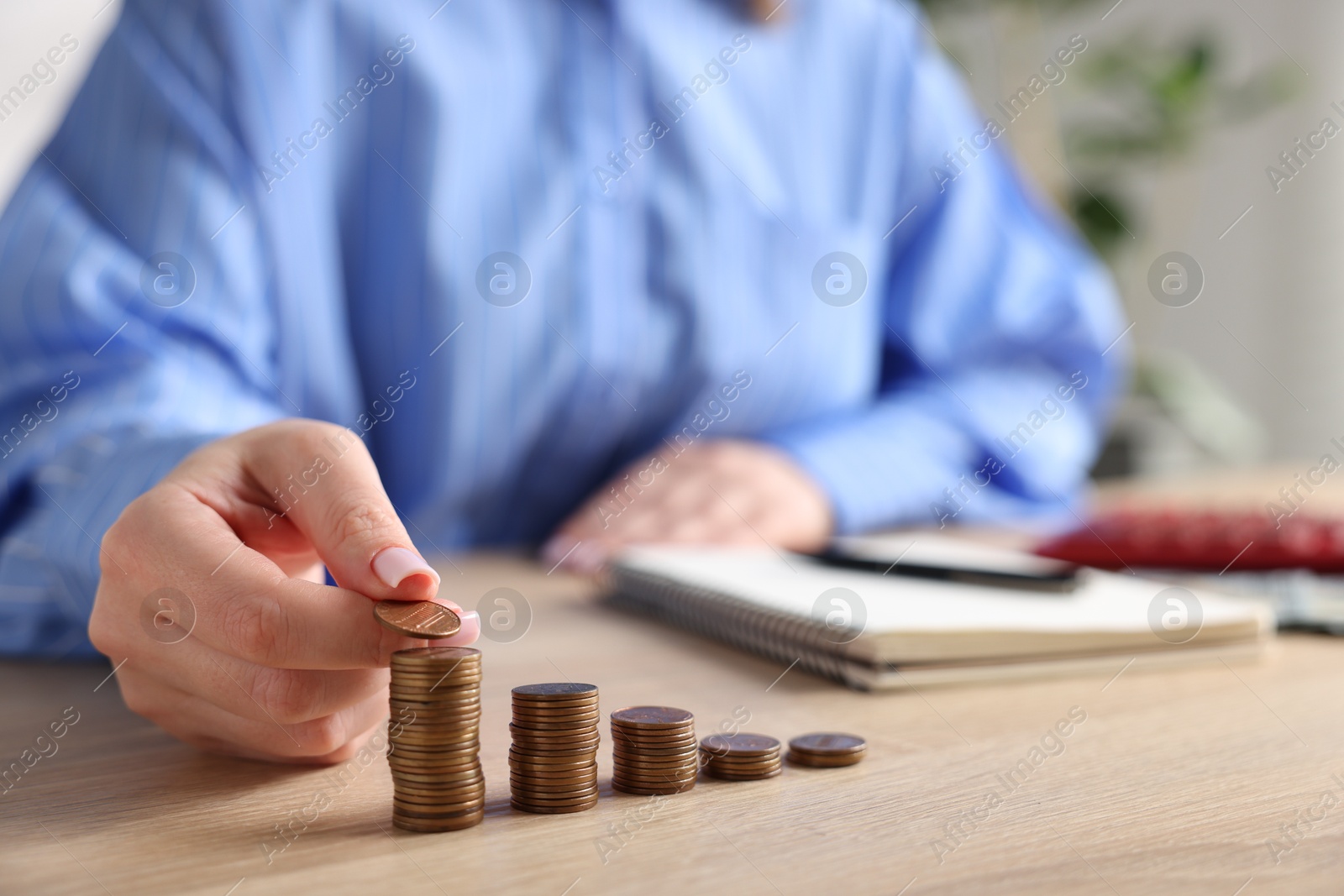Woman stacking coins at wooden table, closeup Photo of Woman stacking coins at wooden table, closeup