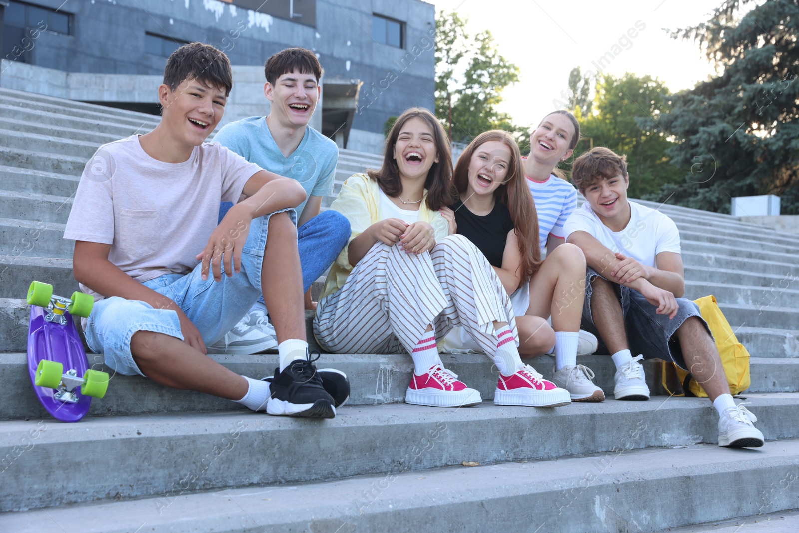 Photo of Group of happy teenage friends spending time together on steps outdoors