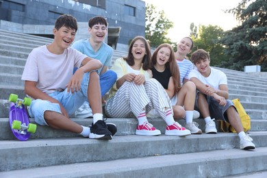 Photo of Group of happy teenage friends spending time together on steps outdoors