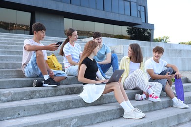 Photo of Group of happy teenage friends spending time together on steps outdoors