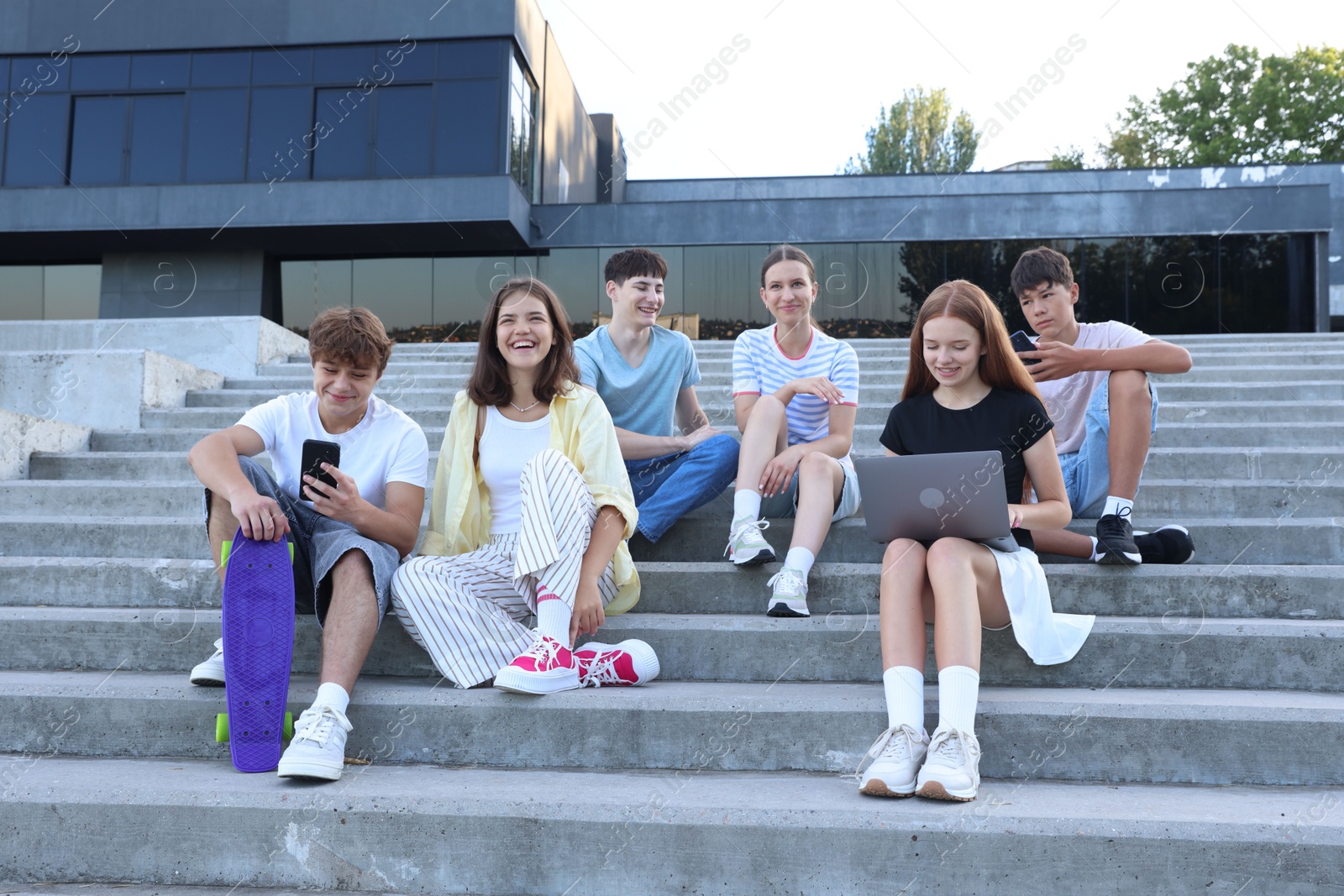Photo of Group of happy teenage friends spending time together on steps outdoors