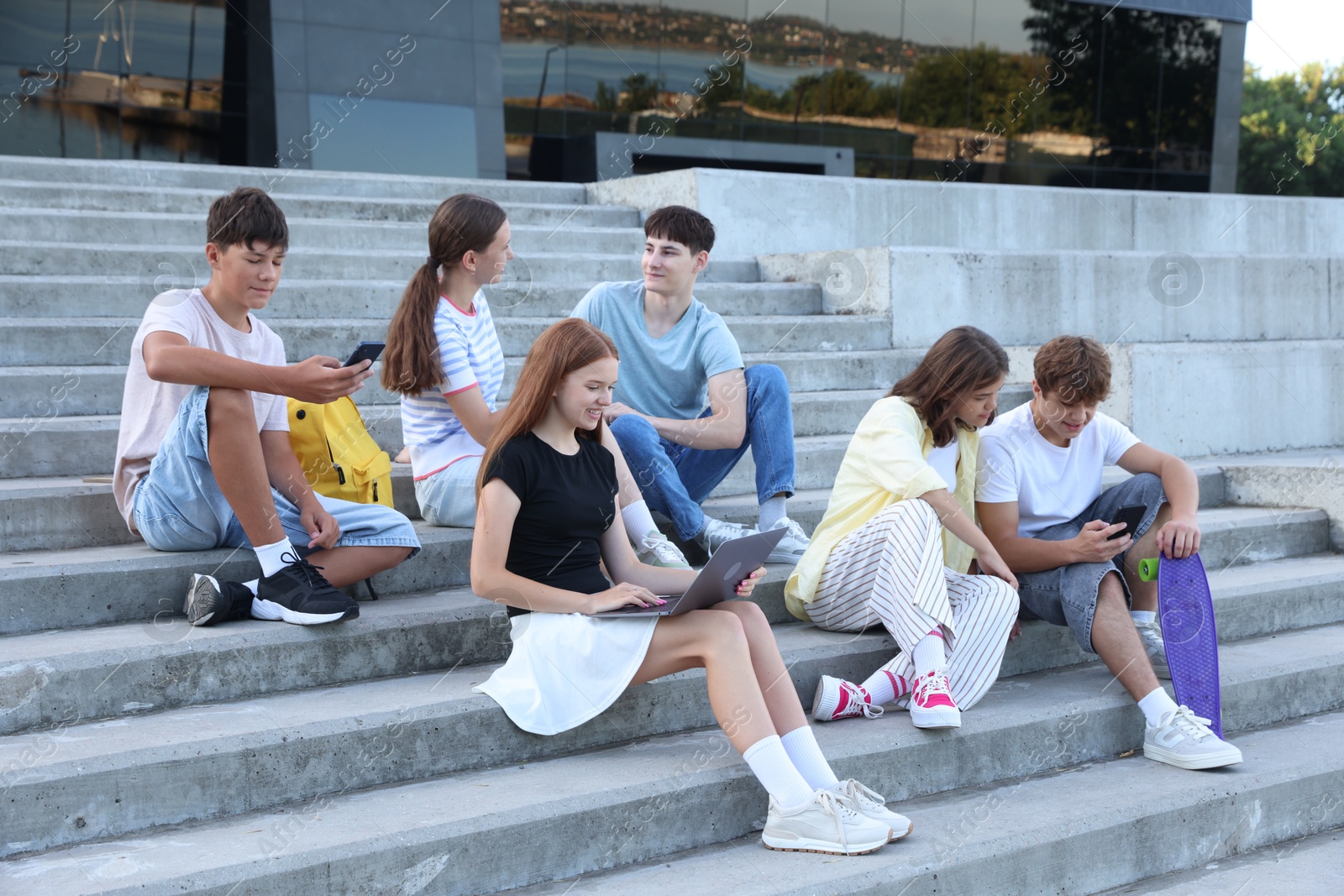 Photo of Group of happy teenage friends spending time together on steps outdoors
