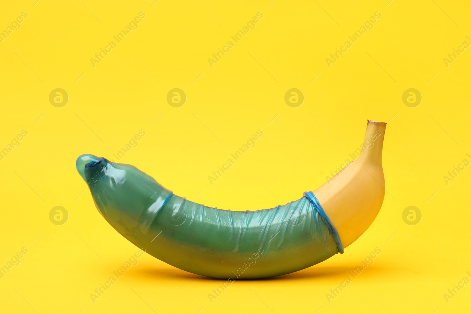 Photo of Sex education. Banana with condom on yellow background