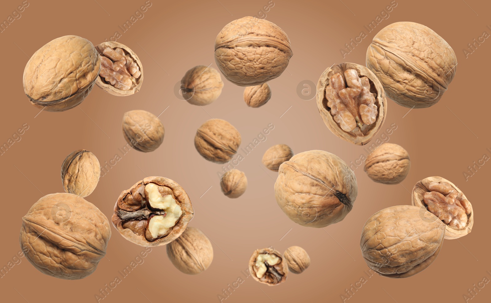 Image of Walnuts in shell swirling in air against pale brown background
