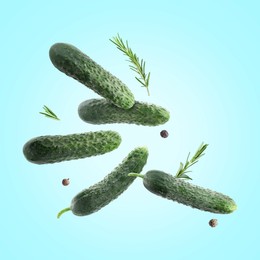 Image of Fresh cucumbers and rosemary falling against light blue background