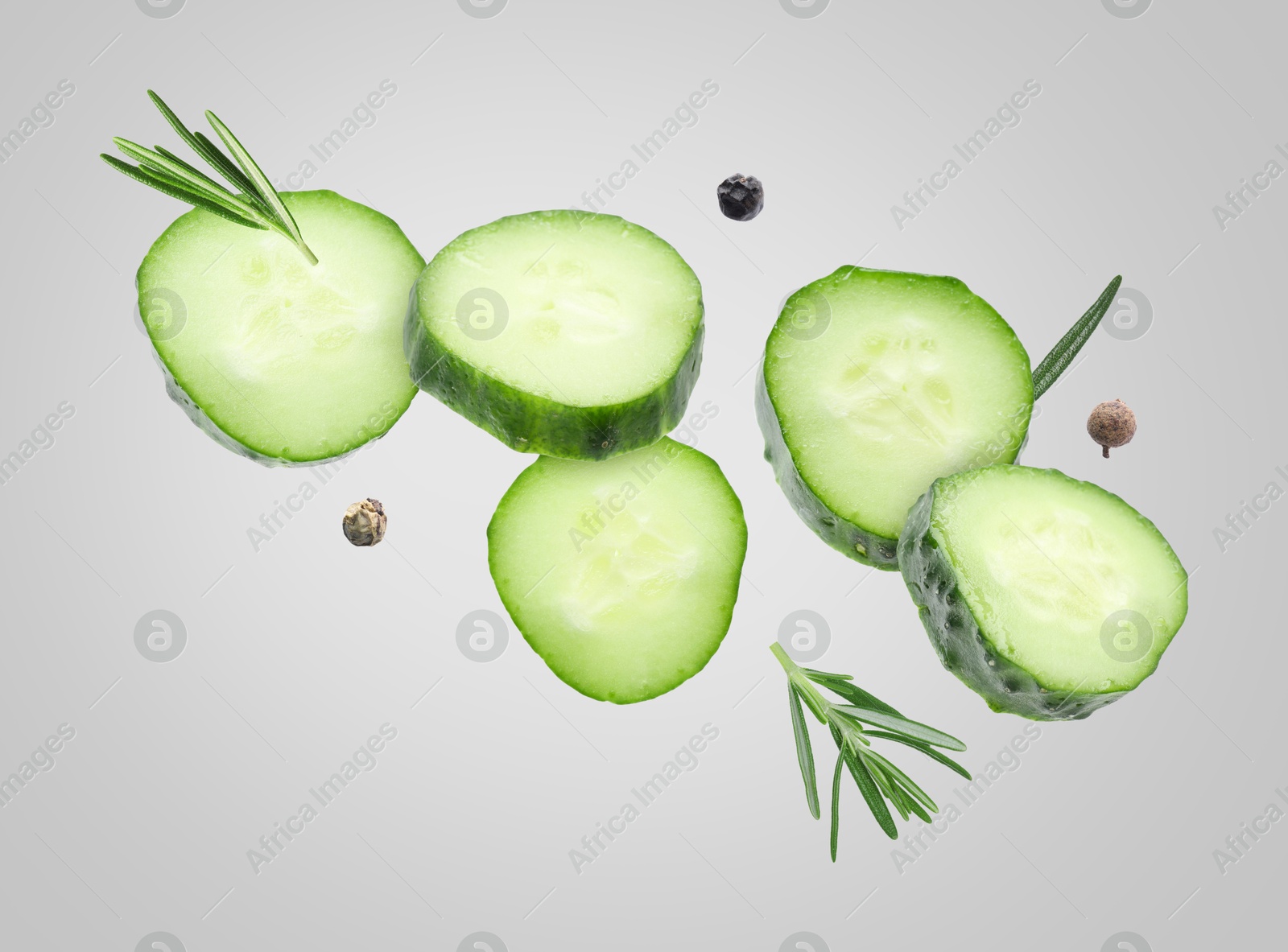 Image of Cucumber slices and rosemary flying against grey background