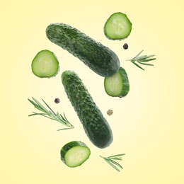 Image of Fresh cucumbers and rosemary falling against beige background