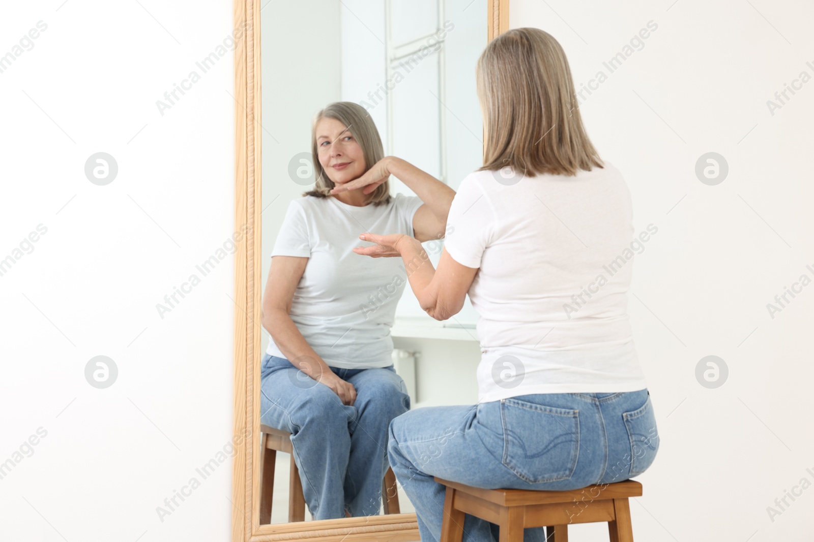 Image of Beautiful senior woman looking at herself in mirror indoors. Mental health