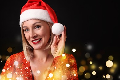 Image of Smiling woman with perfect makeup in Santa hat on black background with bokeh lights