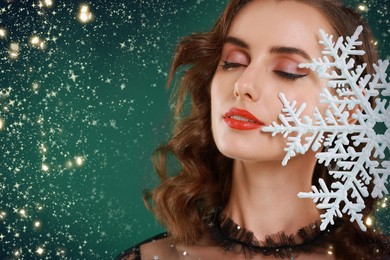 Image of Woman with perfect makeup holding decorative snowflake on green background with magic lights