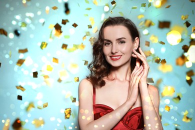 Image of Smiling woman with perfect makeup under falling confetti on festive background