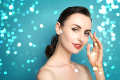Image of Woman with perfect makeup against light blue background with bokeh lights