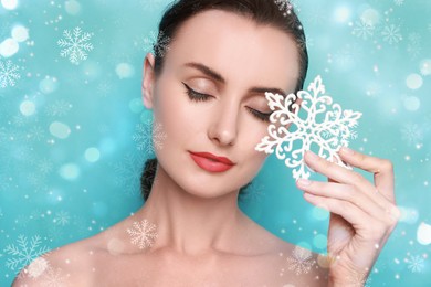Image of Woman with perfect makeup holding decorative snowflake on festive light blue background