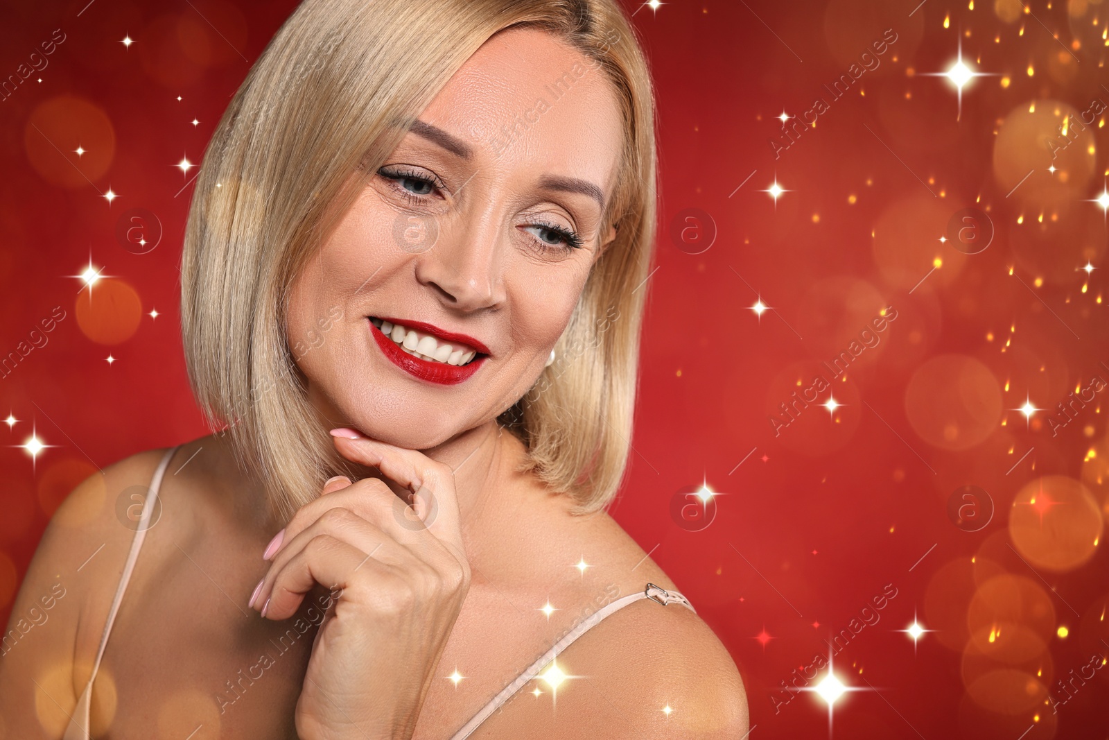 Smiling woman with perfect makeup on red background with magic lights Image of Smiling woman with perfect makeup on red background with magic lights