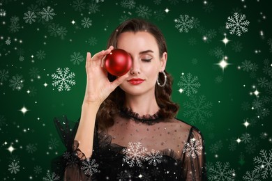 Image of Woman with perfect makeup holding Christmas bauble on green background with snowflakes