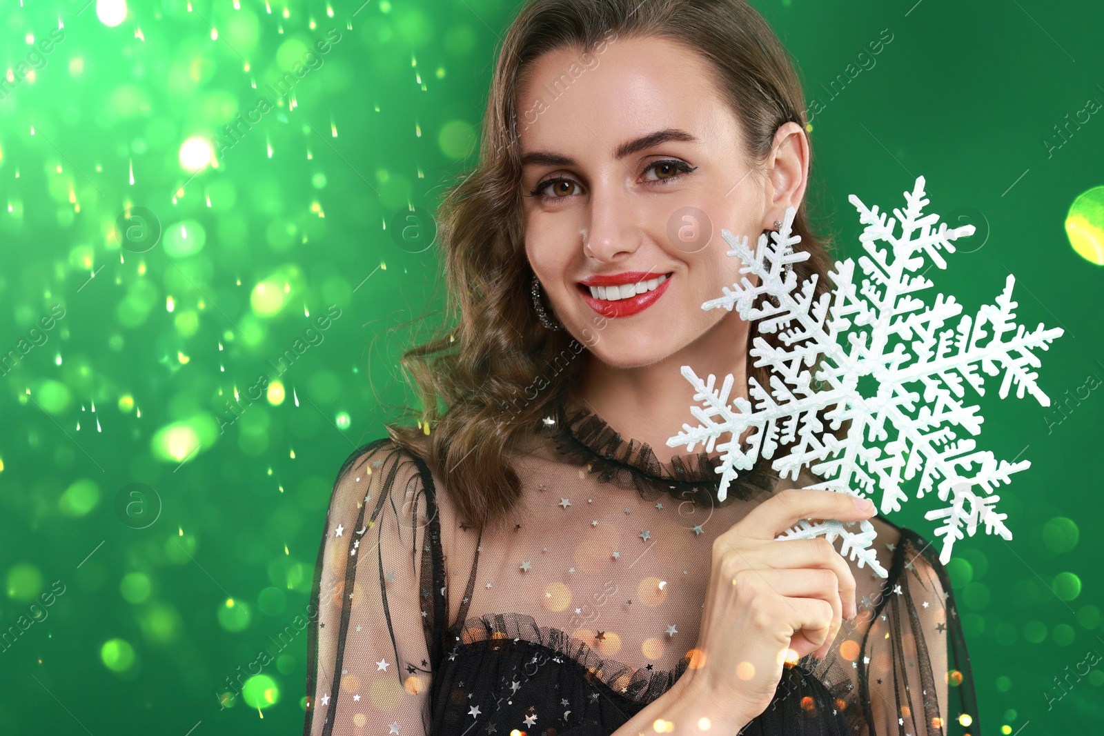 Smiling woman with perfect makeup holding decorative snowflake on green background with bokeh lights Image of Smiling woman with perfect makeup holding decorative snowflake on green background with bokeh lights