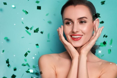 Image of Smiling woman with perfect makeup under falling confetti on light blue background