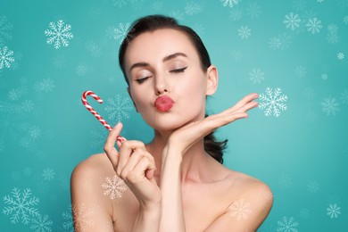 Image of Woman with beautiful makeup holding Christmas candy cane on turquoise background with snowflakes