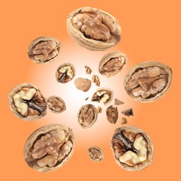 Image of Walnuts in shell swirling in air against coral color background