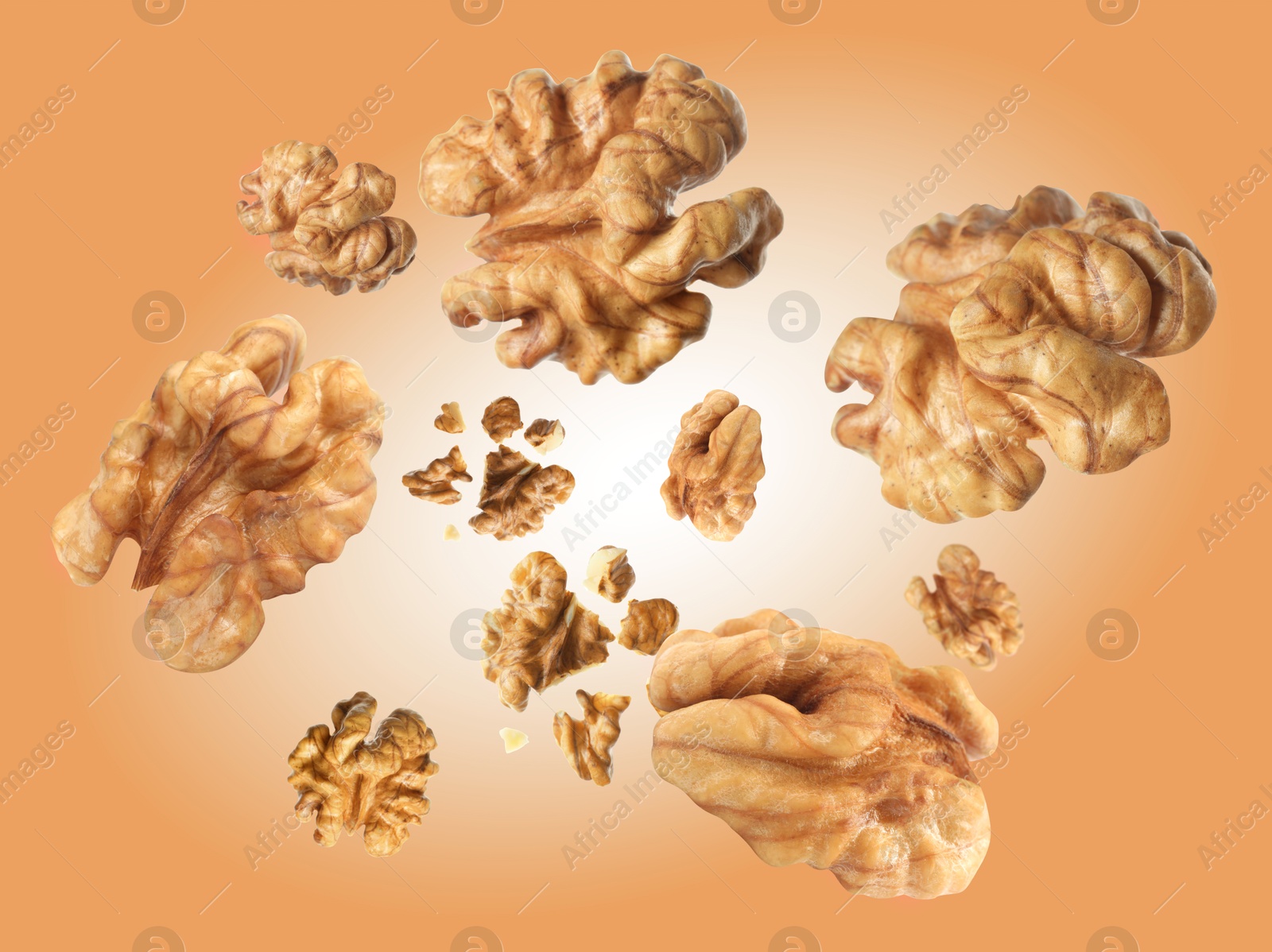 Image of Walnuts swirling in air against coral color background