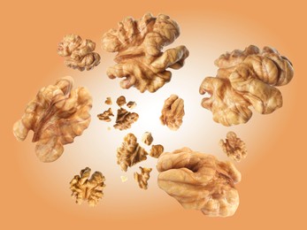 Image of Walnuts swirling in air against coral color background