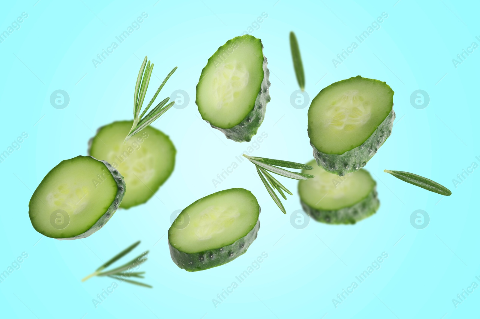 Image of Cucumber slices and rosemary flying against light blue background