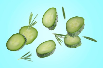 Image of Cucumber slices and rosemary flying against light blue background