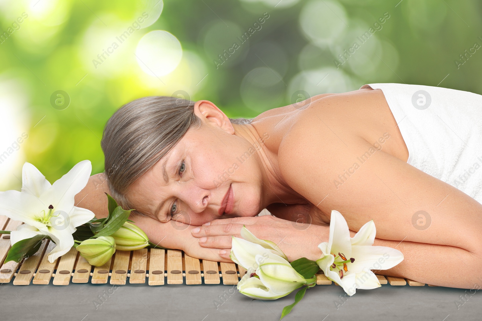Beautiful woman relaxing on bamboo mat against blurred green background. Spa center Image of Beautiful woman relaxing on bamboo mat against blurred green background. Spa center