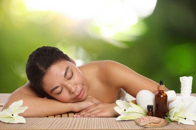 Image of Beautiful woman relaxing on bamboo mat against blurred green background. Spa center