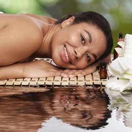 Image of Beautiful woman relaxing on bamboo mat against blurred background. Spa center