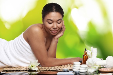 Image of Beautiful woman relaxing on bamboo mat against blurred green background. Spa center