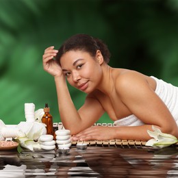 Image of Beautiful woman relaxing on bamboo mat against blurred green background. Spa center