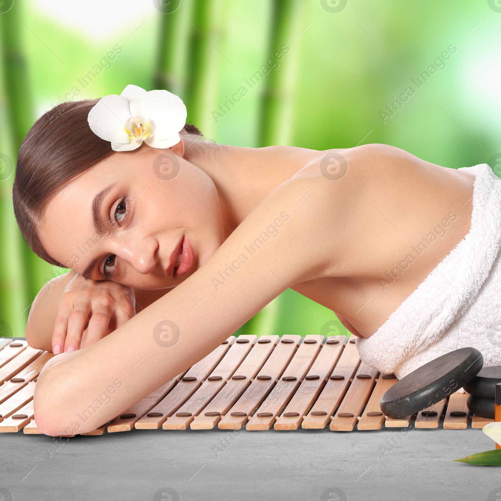 Beautiful woman relaxing on bamboo mat against blurred green background. Spa center Image of Beautiful woman relaxing on bamboo mat against blurred green background. Spa center